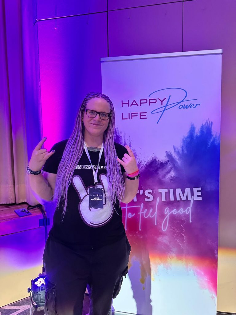 Bloggerin steht vor dem Plakat des Event "Happy Power Days"