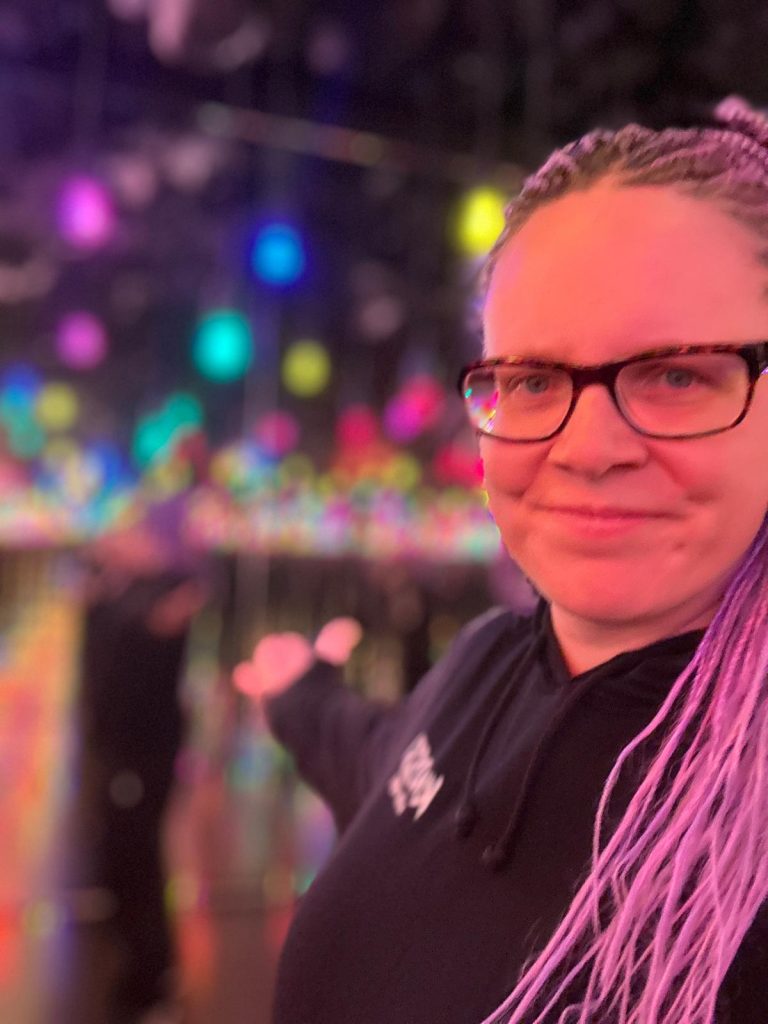 Ein Bild aus einem Spiegelraum mit bunten Discokugel und die Bloggerin zeigt darauf